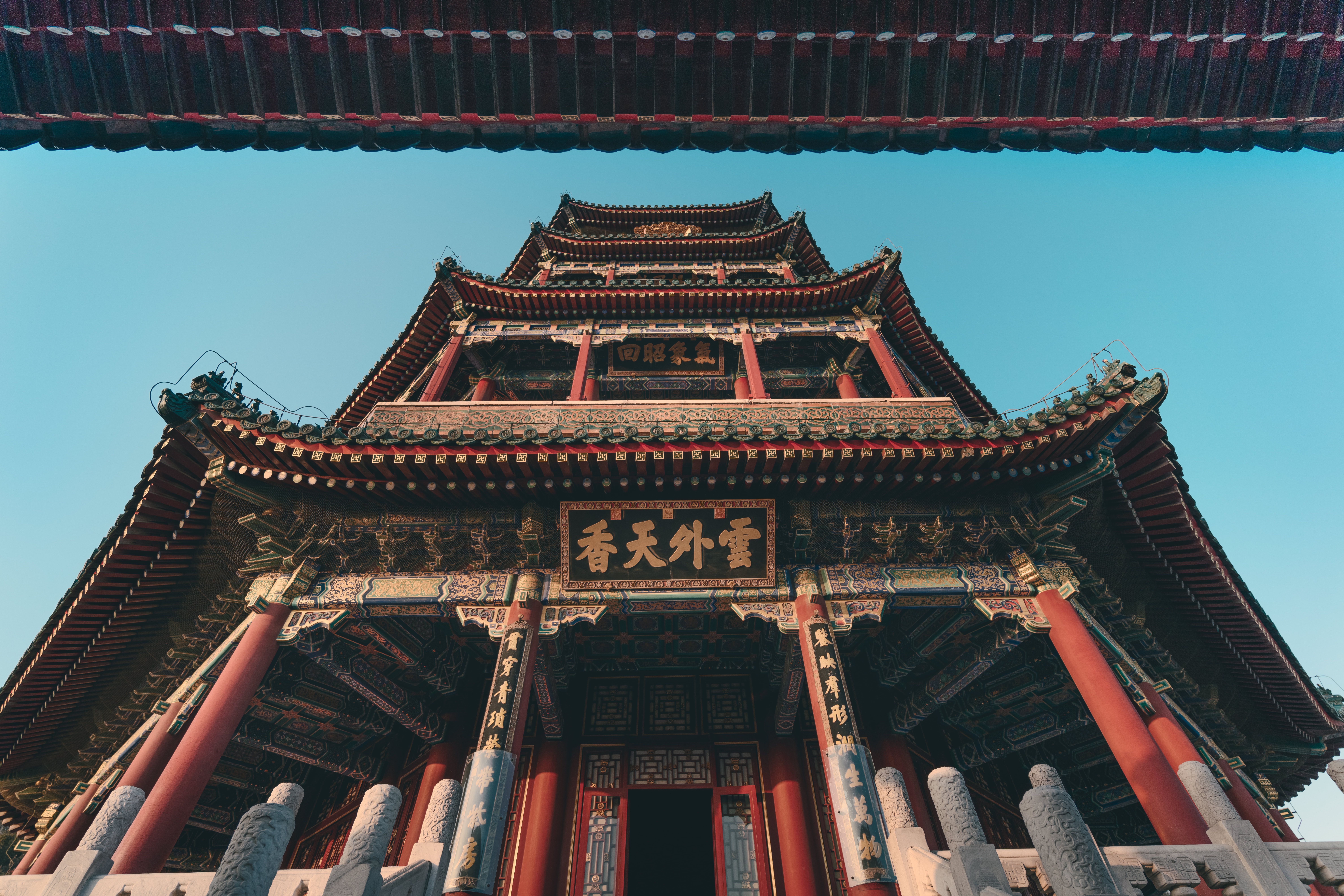 Low angle view of the ornate Summer Palace pagoda with clear blue sky, emphasizing intricate designs.