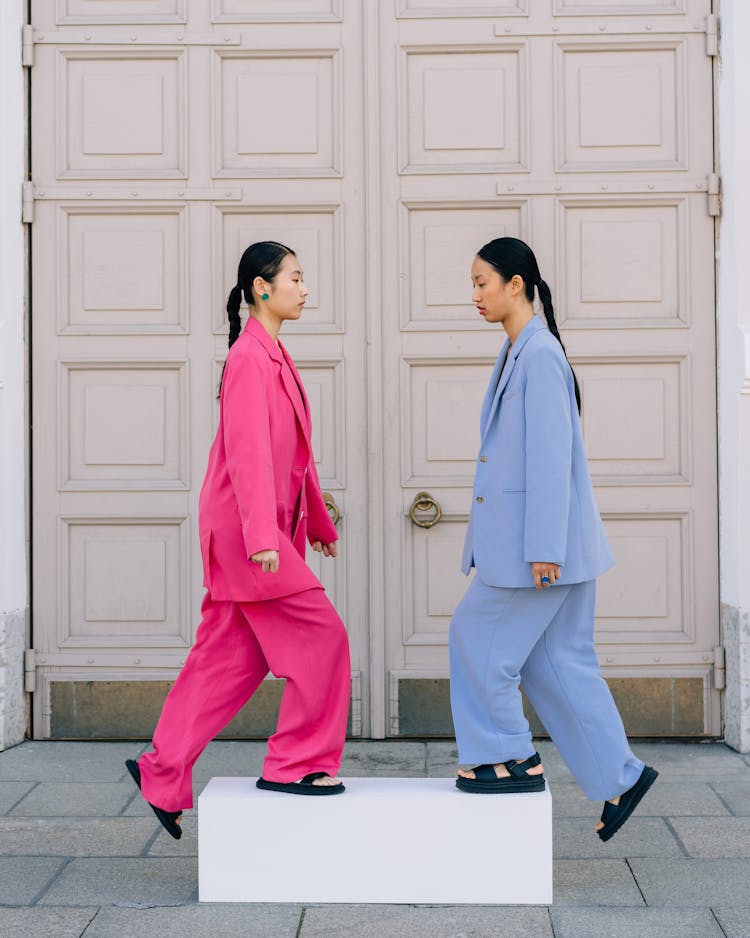 A Woman In A Pink Blazer Walking Near Another Woman