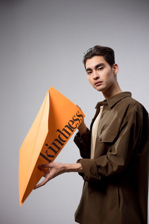 Free Studio shot of a man holding an oversized paper airplane with the word 'kindness'. Stock Photo