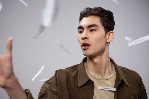 Free A young man in a brown coat throws paper cutouts in the air, capturing a modern, conceptual vibe. Stock Photo