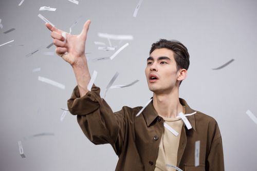 Free A focused young adult male surrounded by floating papers in a studio setting. Stock Photo