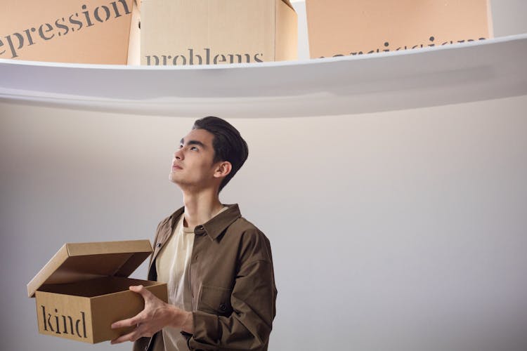 A Man Holding A Box While Looking Up