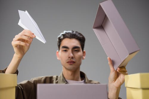 Man Holding Paper Plane over Box