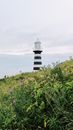 Lighthouse on grassy meadow under cloudy sky