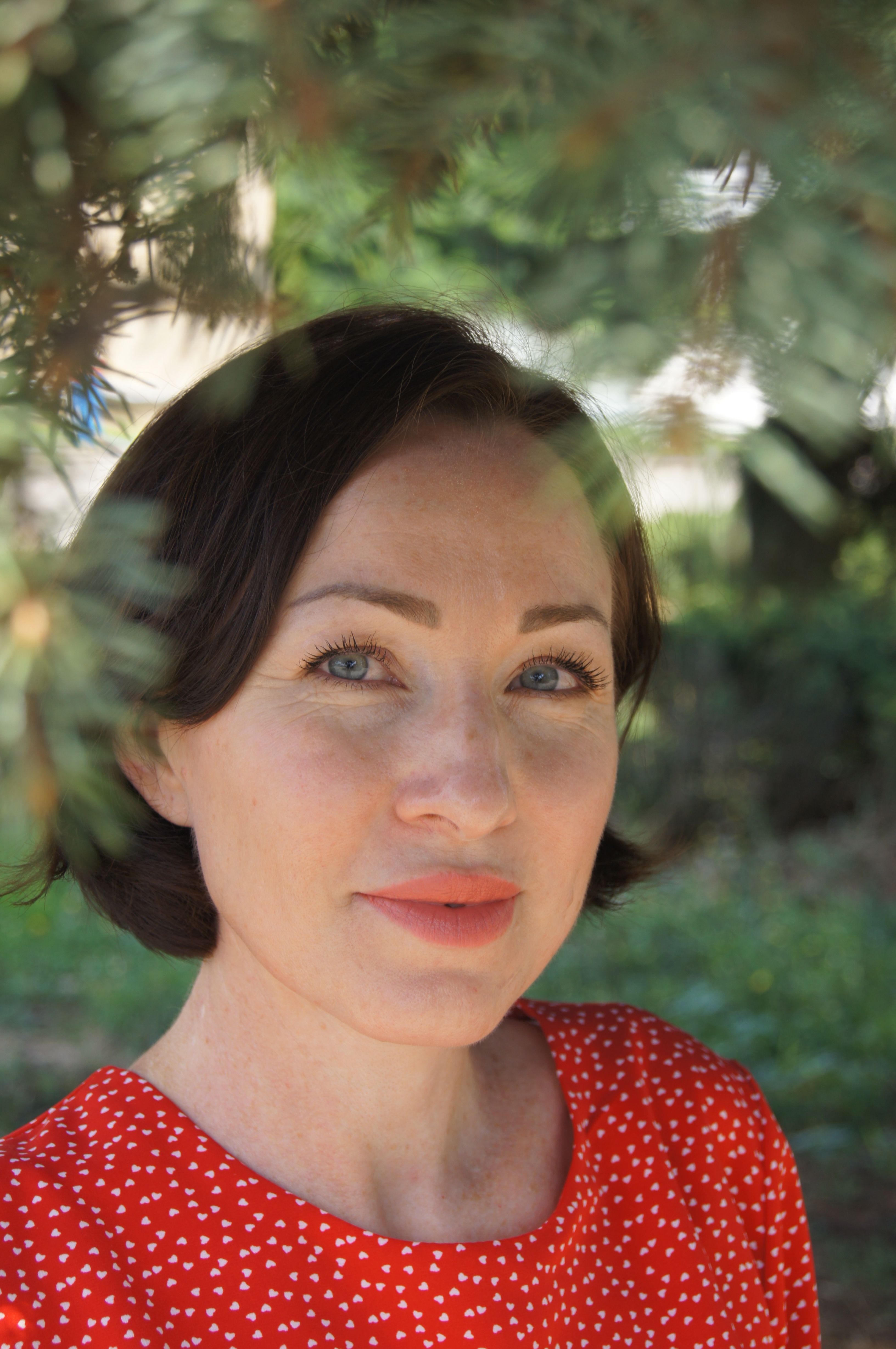 Intimate portrait of a woman in a red dress, captured in natural outdoor setting.