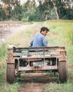 Man in Blue T-shirt Sitting on Brown Wooden Trailer