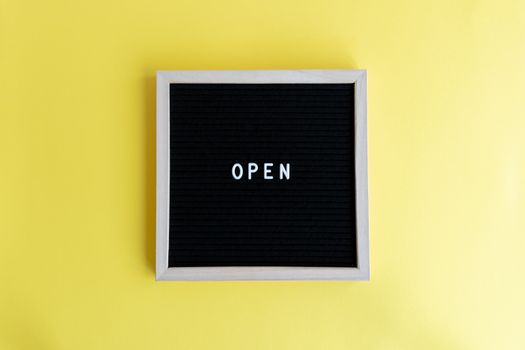 Minimalist blackboard frame displaying the word 'OPEN' on a vibrant yellow background.