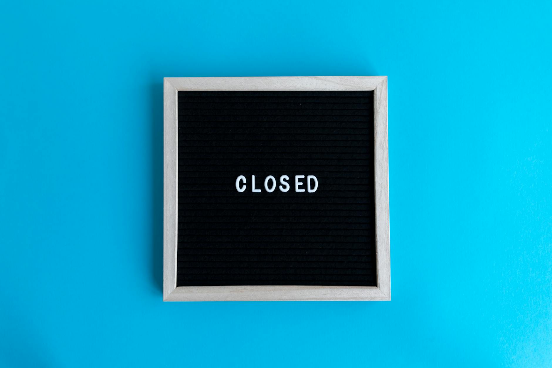 A letter board with 'Closed' displayed against a vibrant blue backdrop, signifying a closure or notice.