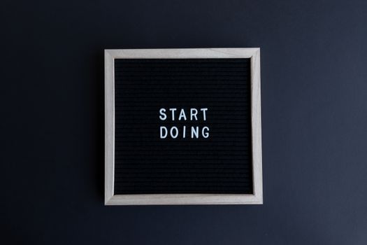Black letter board with the motivational phrase 'Start Doing' in white text on a gray background.