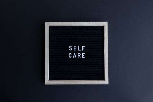 A minimalist letter board displaying 'SELF CARE' on a dark background, promoting mindfulness and well-being.