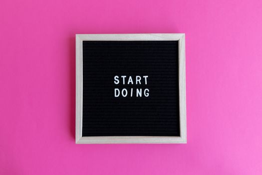 Black letter board with 'Start Doing' motivational text on bright pink background.