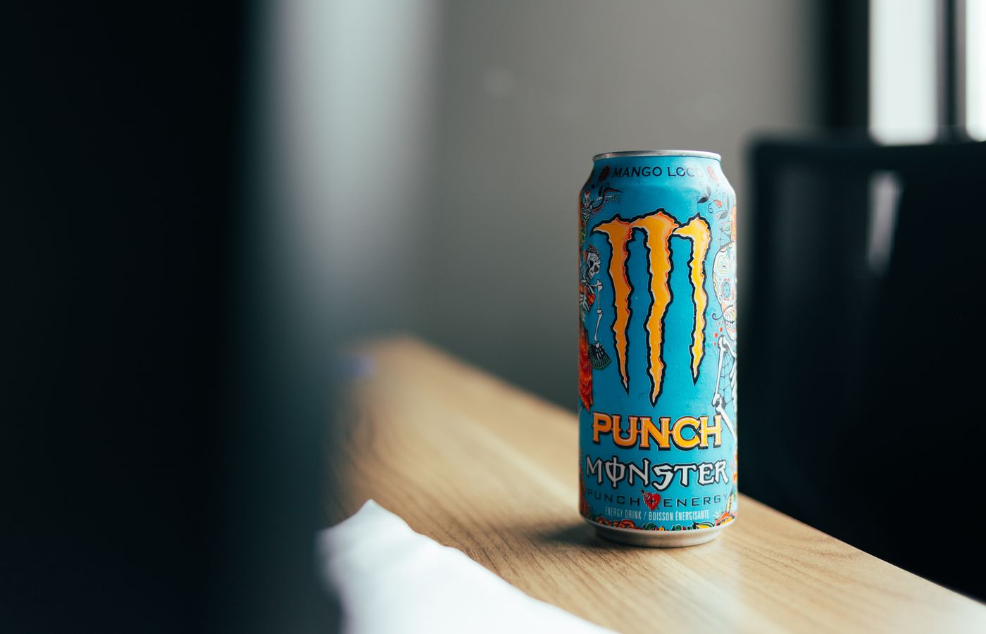 Close-up of a colorful energy drink can on a wooden table indoors.