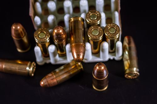Free Detailed view of copper bullets and cartridge cases in a container against a dark background. Stock Photo