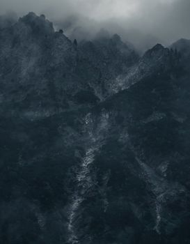 Dramatic foggy mountain landscape showcasing rugged peaks and moody clouds.
