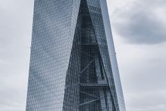 A striking modern skyscraper with glass panels against a cloudy sky in Frankfurt.