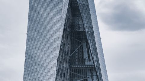 A striking modern skyscraper with glass panels against a cloudy sky in Frankfurt.