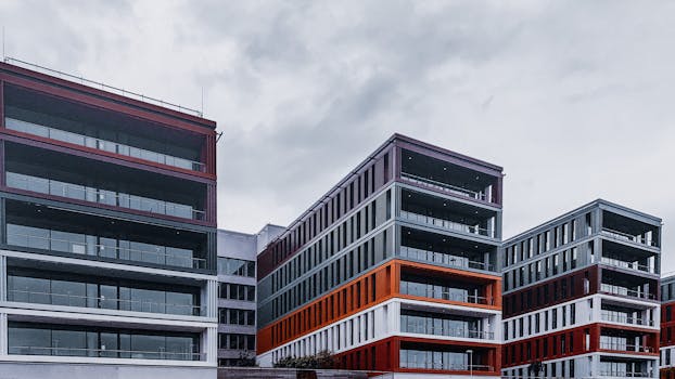 Contemporary office buildings with red and orange accents in an urban setting.