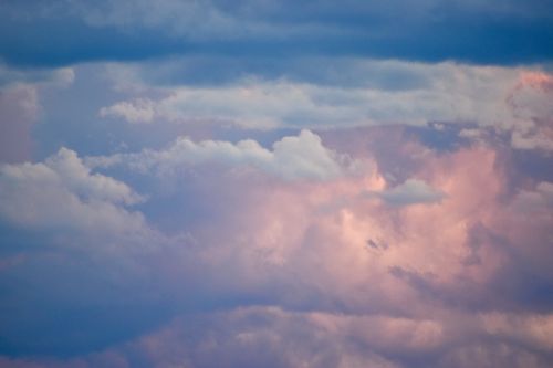 Free A serene sunset cloudscape featuring vibrant pastel colors and fluffy clouds against a calm sky. Stock Photo