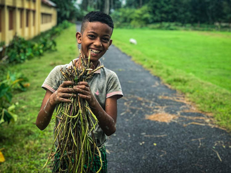 Young Boy Holding Handful Of Plant Sprouts