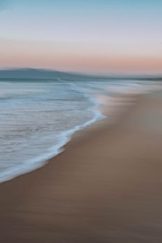 Serene beach scene at sunset with pastel colors and soft waves in Santa Catarina, Brazil.