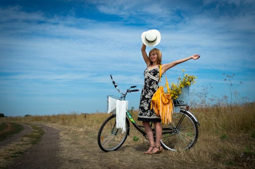 Woman in Black Dress Standing Beside a Bicycle