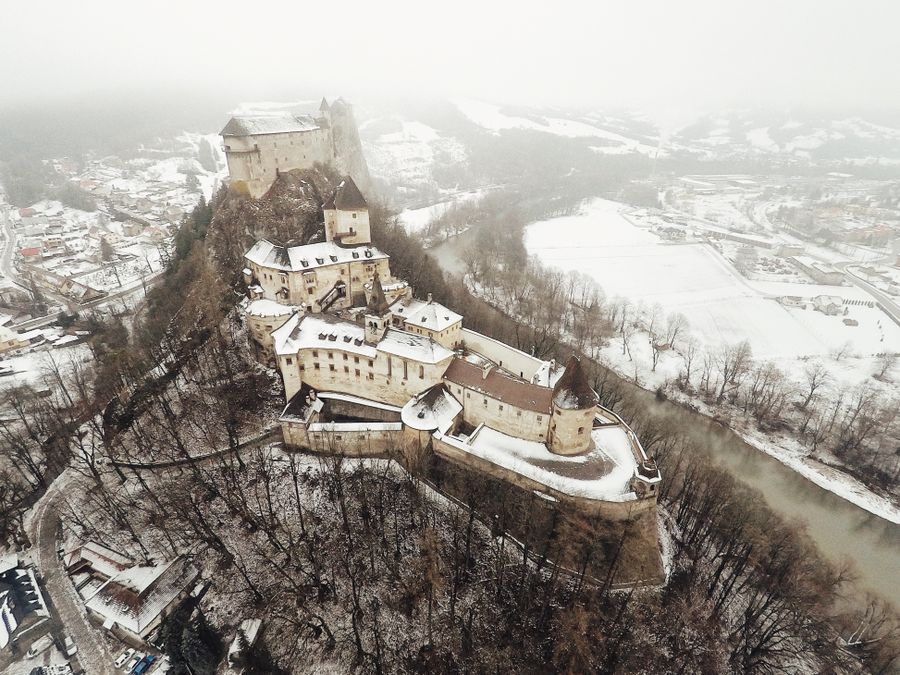 Oravský hrad na skále nad řekou v zasněžené krajině