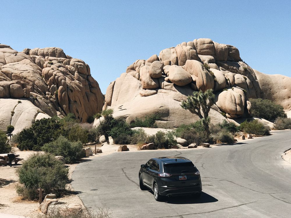 Outside View Car Rocking Car Driving on a Road by a Rock Formation · Free Stock Photo