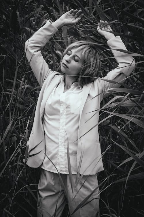 Grayscale Photo of a Woman Raising Her Arms in the Field