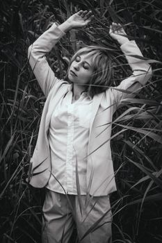 Black and white portrait of a woman with closed eyes posing in tall grass.