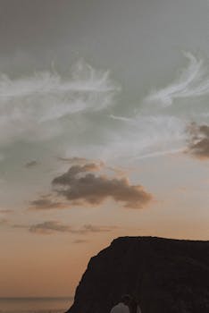 Silhouette of a mountain against a colorful sunset, capturing dramatic cloud formations in the sky.