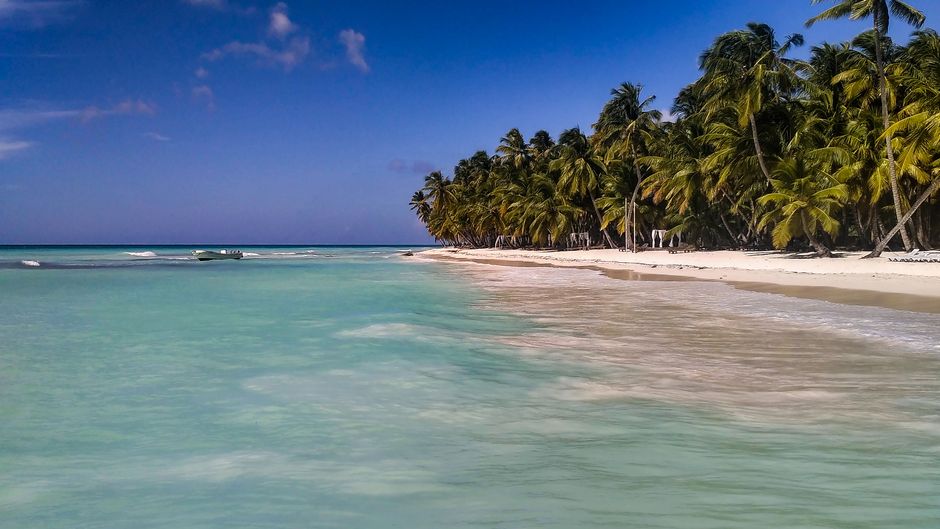 White sand beach and turquoise waters of San Blas Islands, Panama, with a traditional Guna Yala boat
