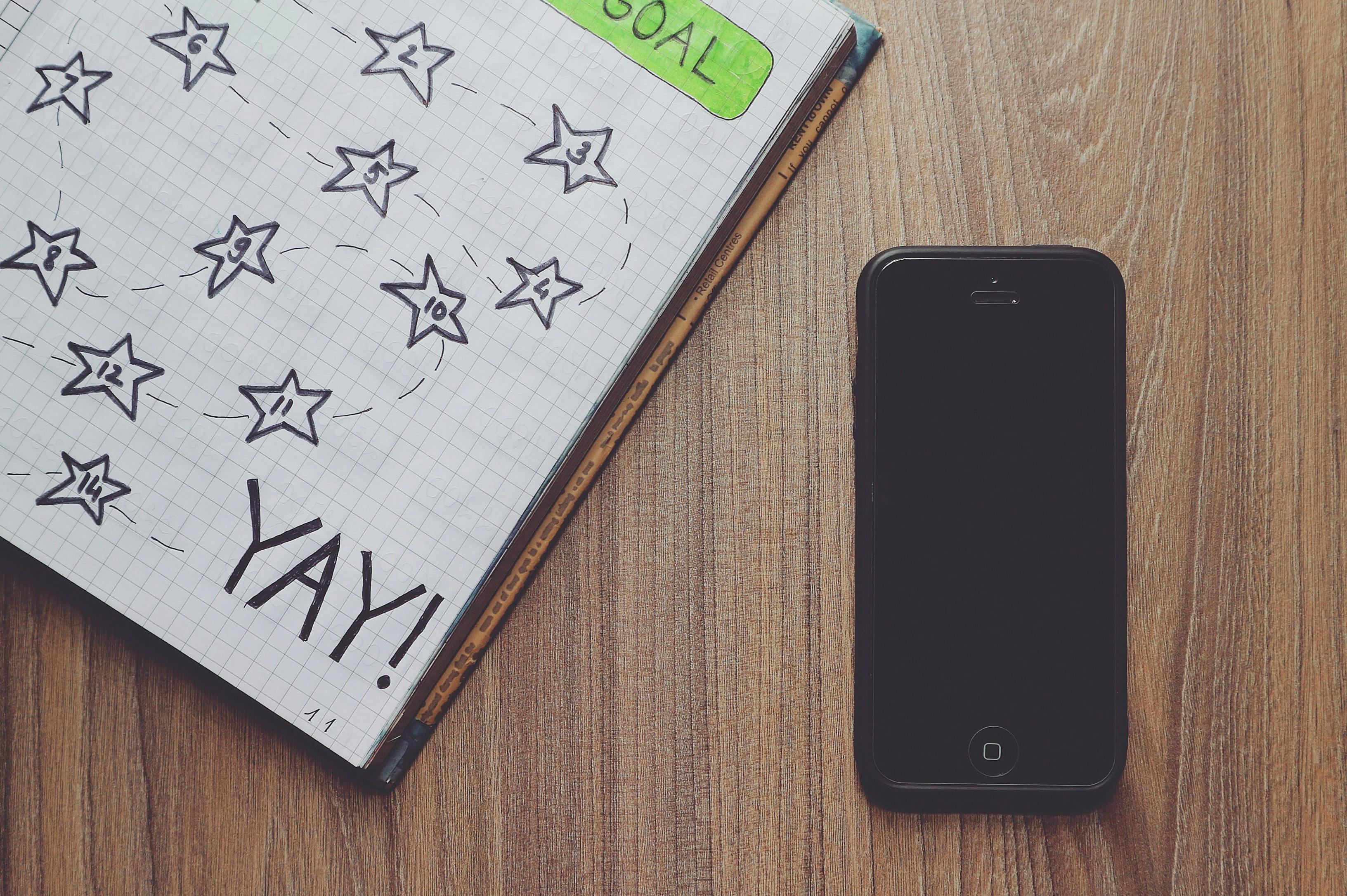 木桌上有一本画着星星和电话的笔记本，体现了创意规划的概念