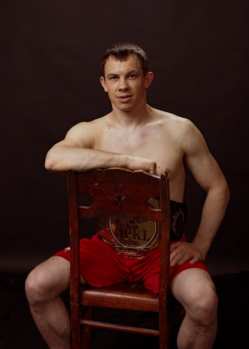 Free Topless Man Sitting on Brown Wooden Chair Stock Photo