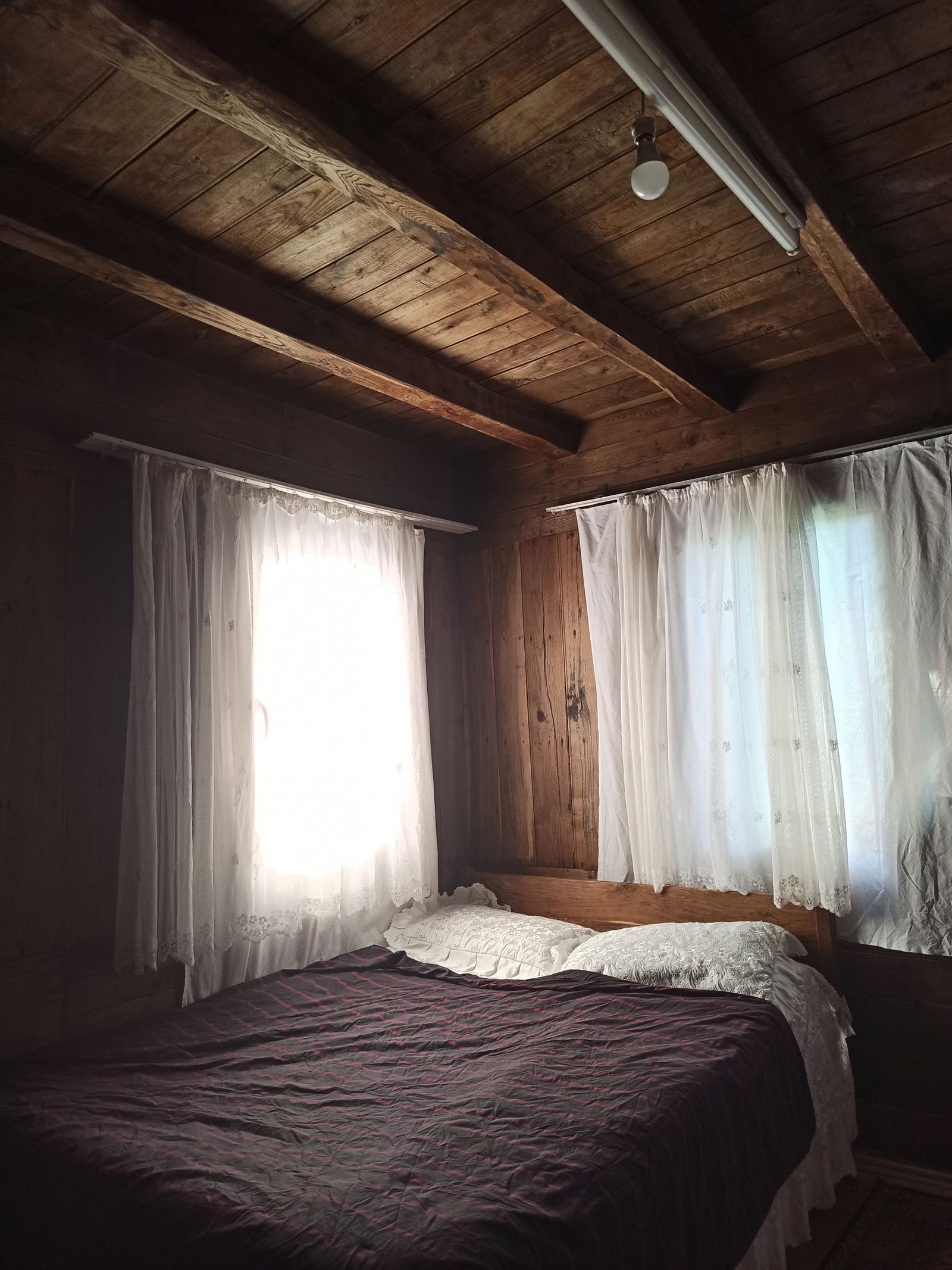 Warm rustic bedroom with wooden walls and soft natural light