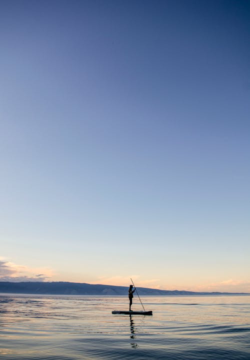 Silhouette of a Person Standing on Seashore during Sunset