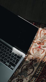A laptop on a patterned textile with natural sunlight highlighting the setup.