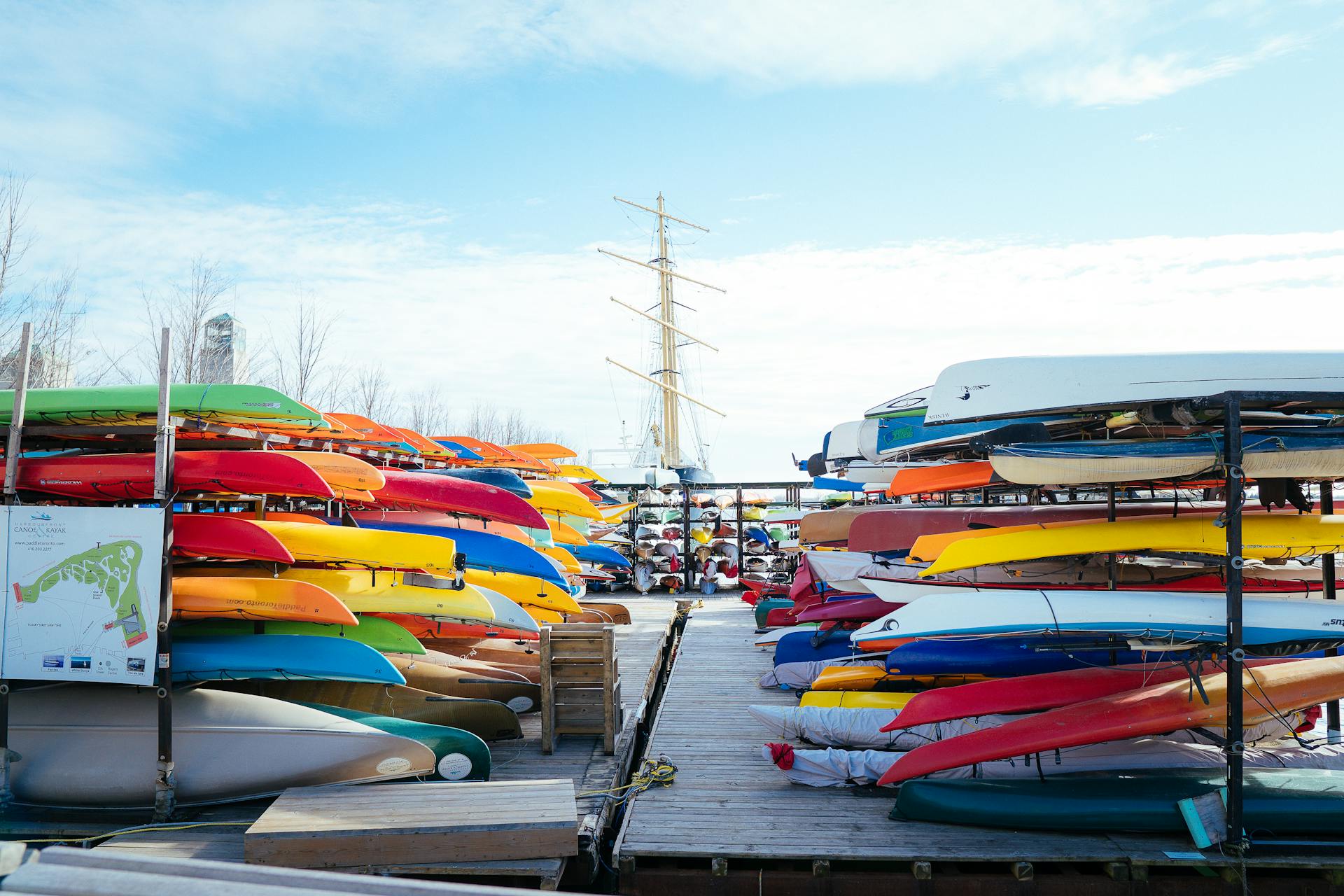 Vibrant canoes and kayaks neatly stacked on a dock under a blue sky, perfect for recreational activities.