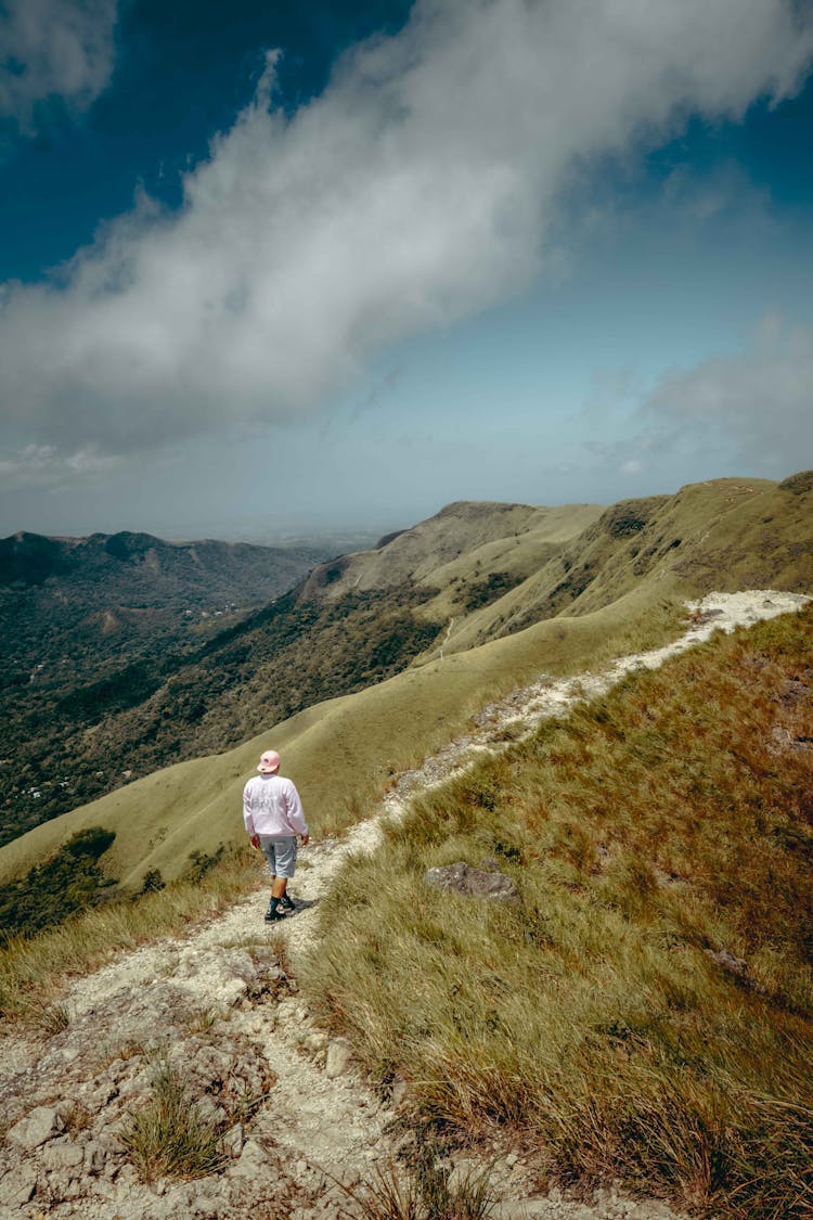 Person Walking On Trail Through Mountain Tops