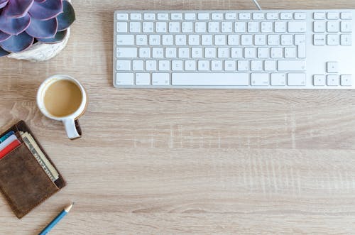 Free Cup of Coffee Near Keyboard on Table Top Stock Photo