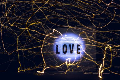 Free Creative abstract art featuring glowing neon lights and the word 'LOVE' on a dark background. Stock Photo