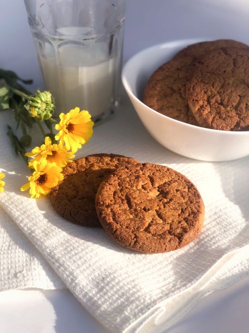 Free Delicious cookies paired with a glass of milk and yellow flowers in a cozy setting. Stock Photo