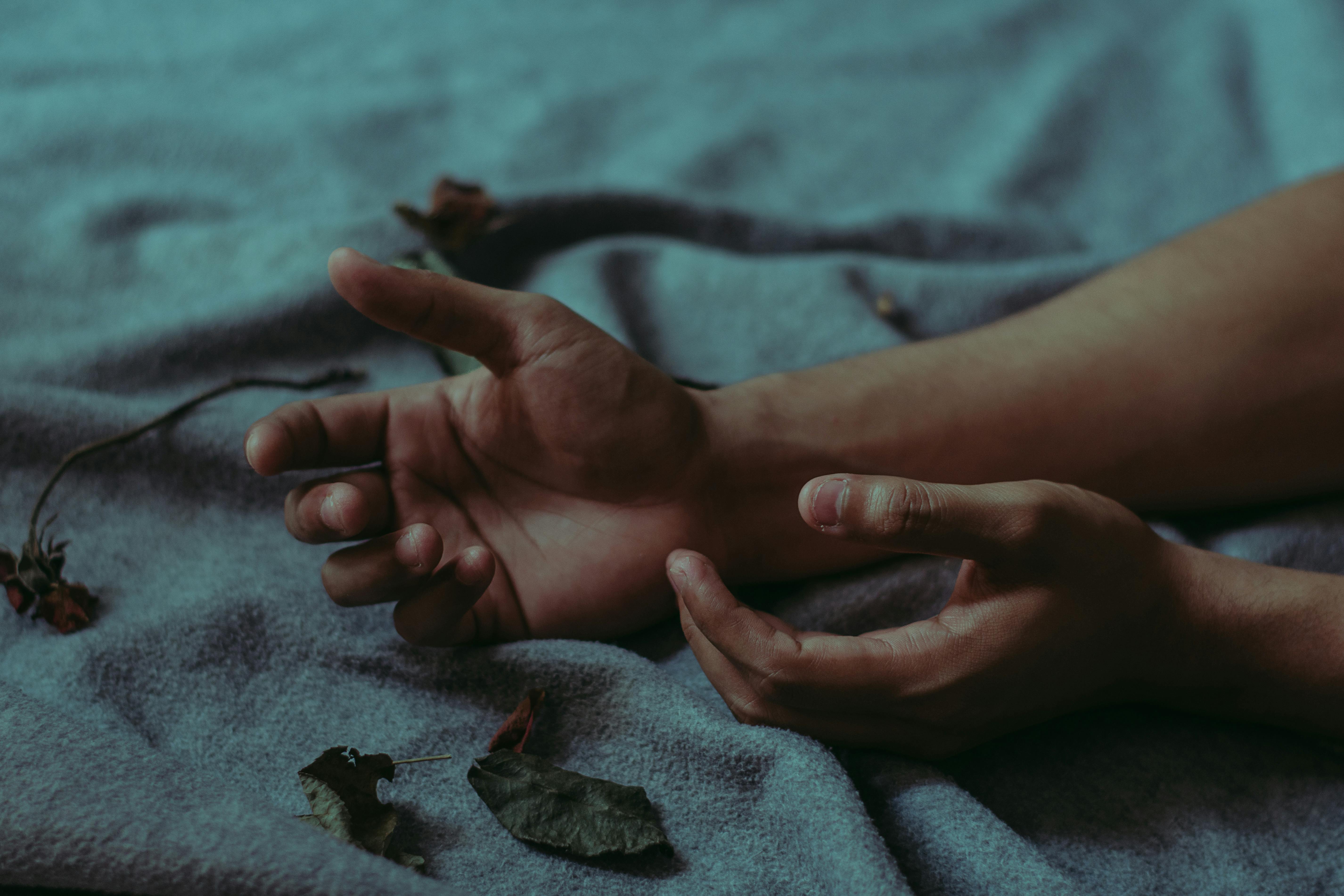 特写镜头中，双手放在铺满干树叶的毯子上，营造出忧郁的氛围