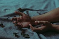 特写镜头中，双手放在铺满干树叶的毯子上，营造出忧郁的氛围