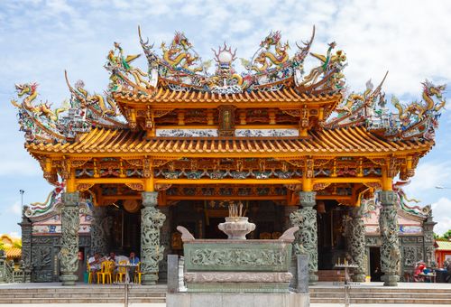 Free Front view of an ornate Chinese temple with intricate dragon sculptures on the roof, showcasing traditional architecture. Stock Photo