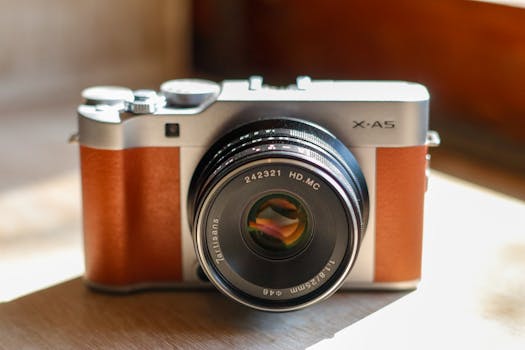 Close-up of a vintage style mirrorless camera with leather finish on a wooden table.