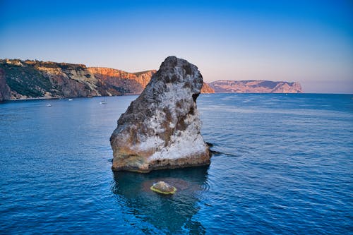 Big Rock Formation on the Middle of the Sea Under Blue Sky