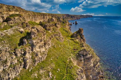 Free Stunning aerial view of coastal cliffs and clear blue sea on a sunny day, showcasing natural beauty. Stock Photo