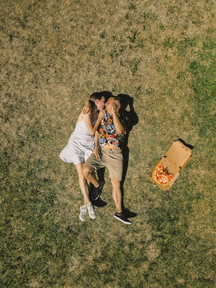 A Sweet Couple Lying On A Grass Field While Cuddling