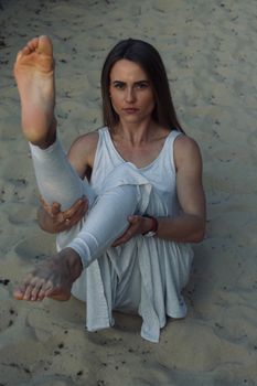 Focused woman stretching on a sandy beach, showcasing yoga pose and tranquility.