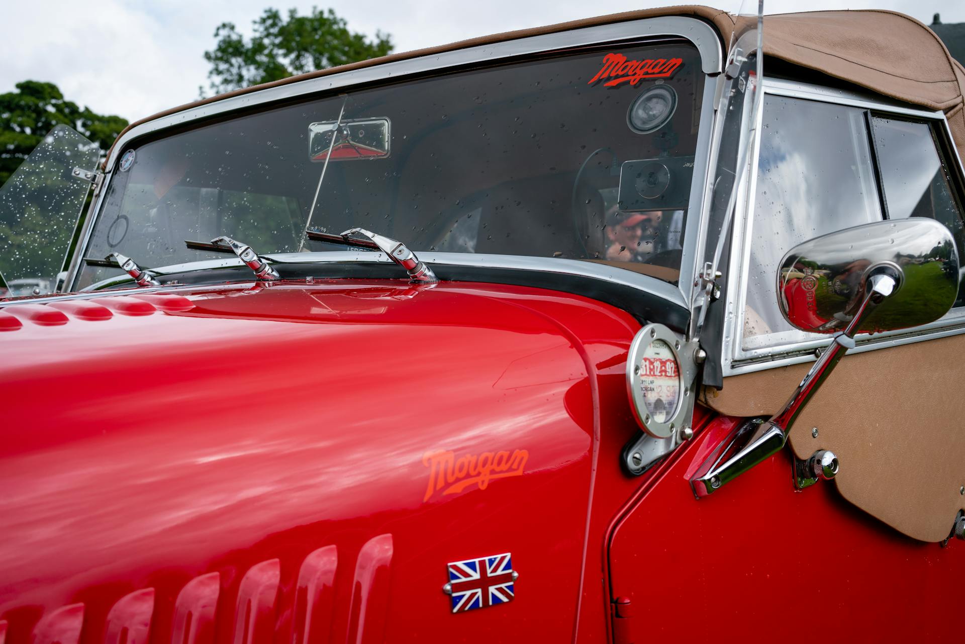 Detailed view of a vintage red Morgan Plus 8 car with Union Jack emblem.